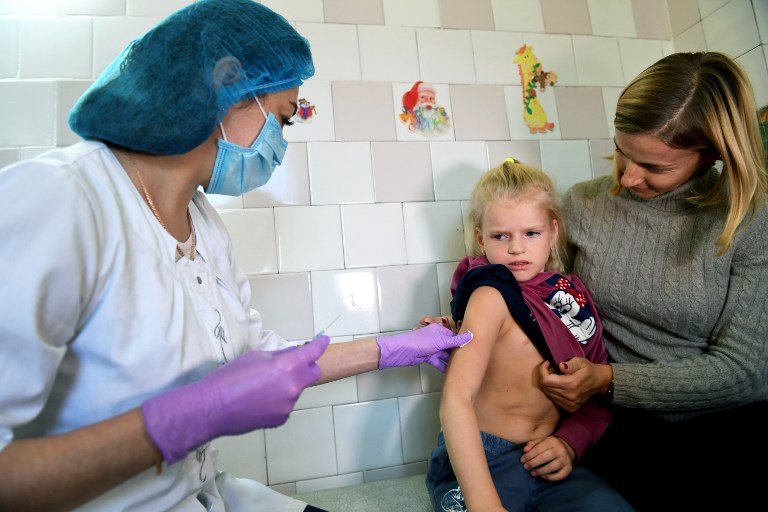 A healthcare worker providing medical care to a child accompanied by her mother in Ukraine