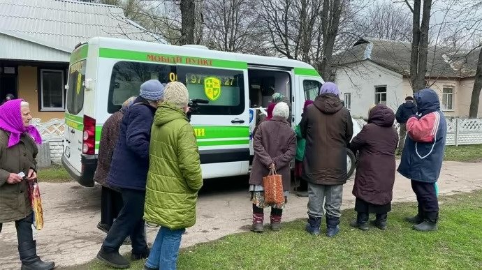 Residents gathering beside a mobile health clinic vehicle in a Ukrainian community.