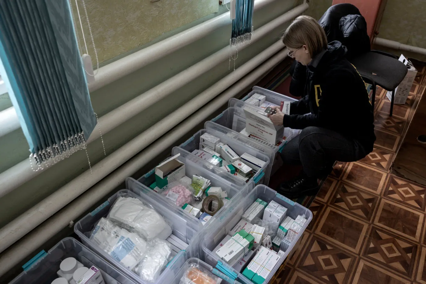A humanitarian worker organizing medicine and medical supplies for rural health assistance in Ukraine.